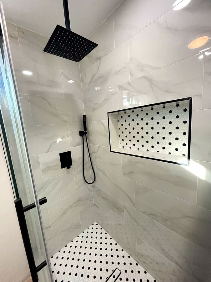 Marble shower with matte-black fixtures and mosaic-lined niche