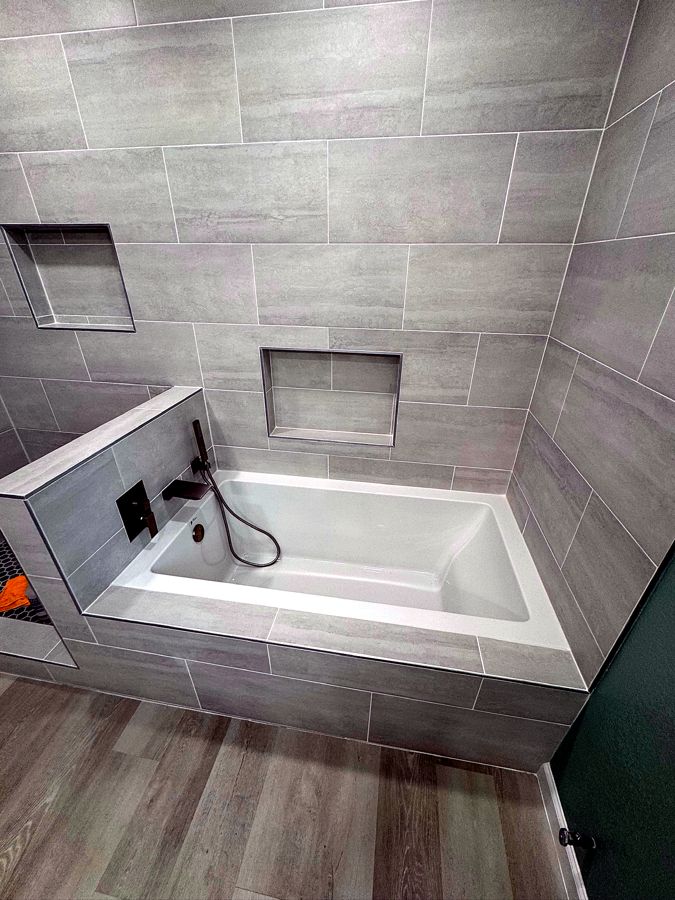Tiled tub surround with matte-black filler and custom storage niches