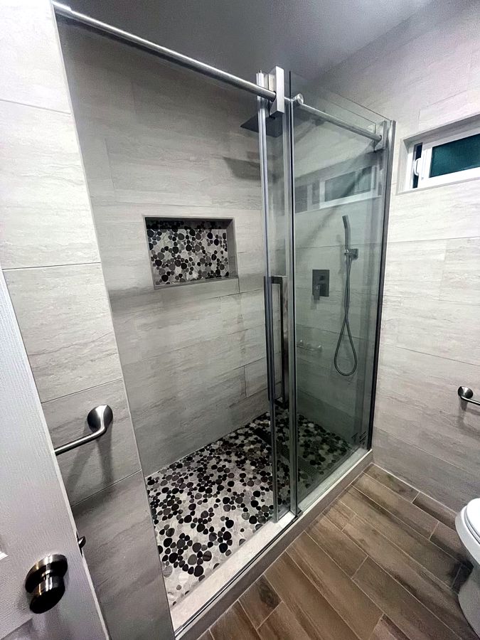 Walk-in shower with pebble floor and glass enclosure