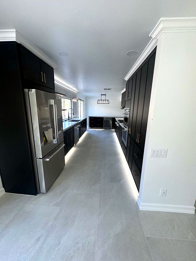 Black cabinetry kitchen with integrated refrigerator and toe-kick lighting