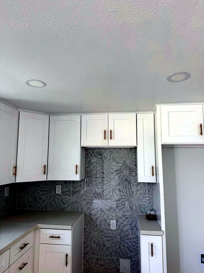 White kitchen with patterned tile backsplash and custom cabinet storage